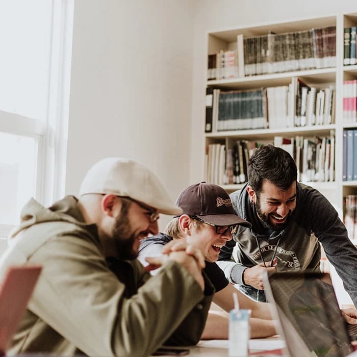 Trois hommes rigolant devant un ordinateur