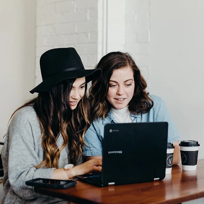 Deux femmes souriantes regardant un ordinateur